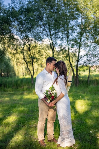 Fröhliche junge Leute in Hochzeitskleidung stehen auf der Wiese und küssen sich