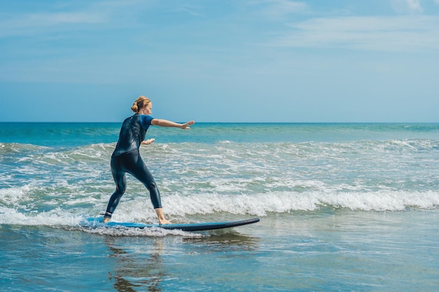 Fröhliche junge Surferin mit blauer Brandung hat Spaß auf kleinen Meereswellen Aktiver Familienlebensstil Menschen Outdoor-Wassersportunterricht und Schwimmaktivität im Sommerurlaub des Surfcamps