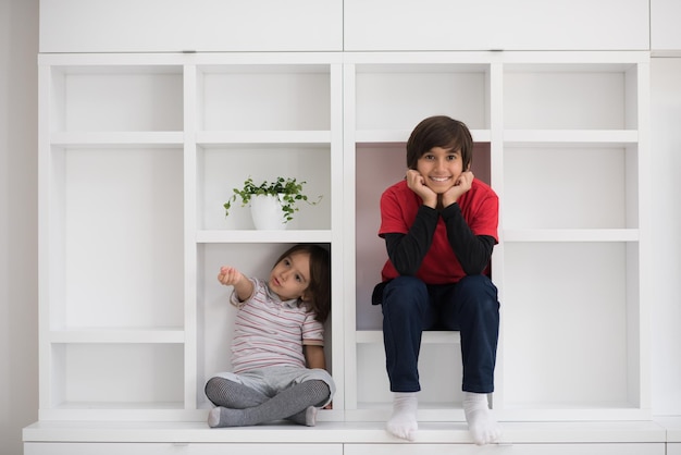 Fröhliche Jungen haben Spaß, während sie in einem neuen modernen Zuhause auf einem Regal posieren