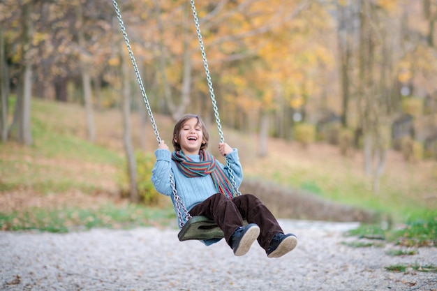 fröhliche kinder amüsieren sich auf einer schaukel kleiner bruder und schwester spielen draußen