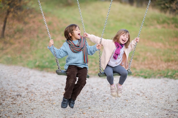 Foto fröhliche kinder amüsieren sich auf einer schaukel kleiner bruder und schwester spielen draußen