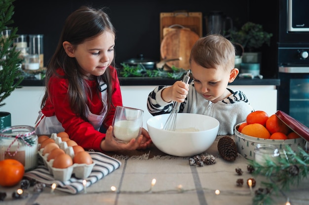 Fröhliche Kinder bereiten Weihnachtsplätzchen in der Küche zu Neujahrskonzept Meisterklasse oder kulinarischer Workshop