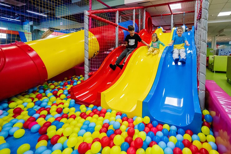 Fröhliche Kinder, die auf dem Spielplatz im Indoor-Spielzentrum spielen Kinderrutschen in farbiger Rutsche in Bälle im Bällebad