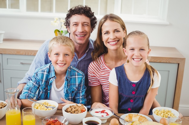 Fröhliche Kinder und Eltern frühstücken am Tisch