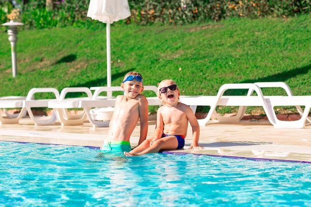 Fröhliche kleine Kinder haben Spaß am Pool des Ferienortes