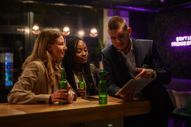 Fröhliche Kollegen trinken nach der Arbeit gemeinsam Bier in der Bar