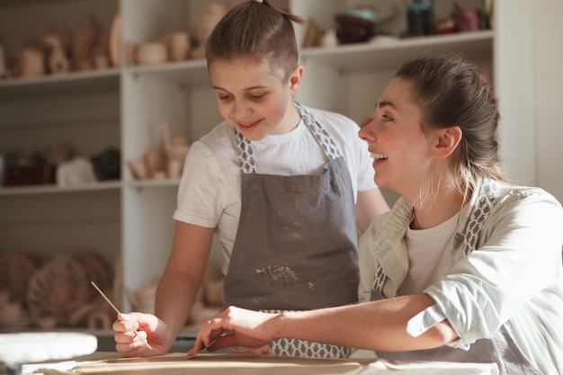 Fröhliche lachende Frau, während sie mit ihrem Sohn im Kunststudio Töpfern lernt