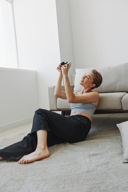 Fröhliche lächelnde Frau, die eine alte Kamera hält und Fotos von sich selbst als Wochenendfotografin in Hauskleidung mit kurzen Haarschnitthaaren ohne Filter auf weißem Hintergrund macht, freier Kopierraum