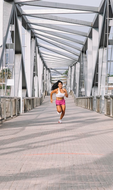 Fröhliche Läuferin, die über eine Stadtbrücke läuft Wellness-Konzept