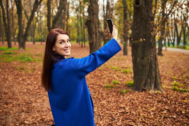 Fröhliche langhaarige Frau mit ihrem neuen Telefon