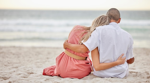 Foto fröhliche liebe und paar an einem strand umarmen sich, während sie gemeinsam den sonnenuntergang am strand und das meer beobachten fröhlicher freund und freundin, die sich in einem sommerurlaub auf dem sand am meerwasser in der natur umarmen