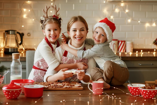 Fröhliche lustige Familienmutter und Kinder backen Weihnachtsplätzchen