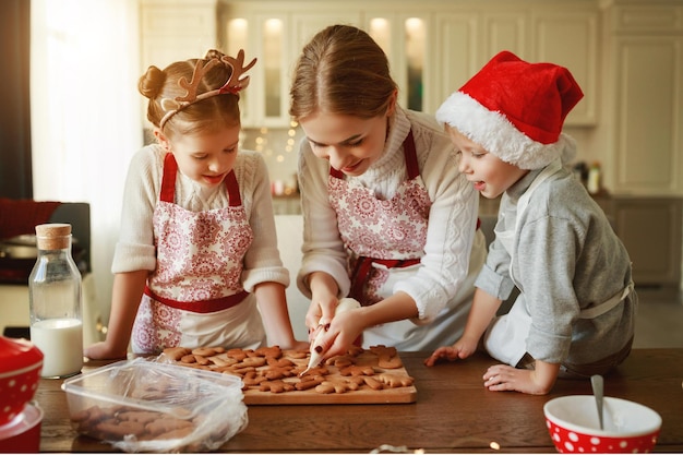 Fröhliche lustige Familienmutter und Kinder backen Weihnachtsplätzchen