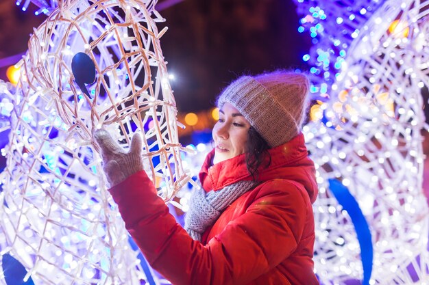 Fröhliche lustige junge Frau mit Winterkleidung Hintergrund Abend Stadt Lichter Beleuchtung Weihnachten