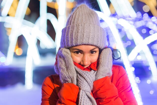 Fröhliche lustige junge Frau mit Winterkleidung Hintergrund Abend Stadt Lichter Beleuchtung Weihnachten