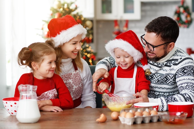 Fröhliche, lustige Mutter, Vater und Kinder backen Weihnachtsplätzchen