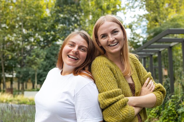 Fröhliche Mädchen, die sich umarmen. Bild von zwei jungen, glücklichen Freundinnen, die im Sommer draußen stehen