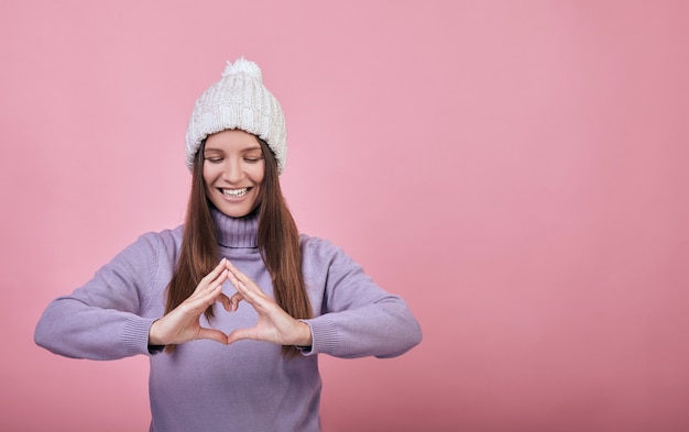 Fröhliche Mädchen in Kleidung im Winter oder springshows ein Herz aus Fingern