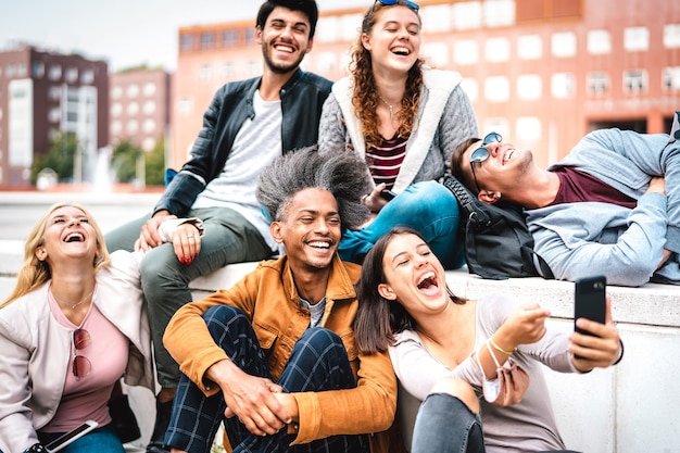 Fröhliche milenial Freunde, die Spaß mit dem Handy auf dem Campus College Yard haben