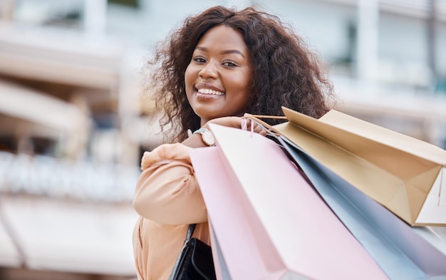 Fröhliche Mode und schwarze Frau, die in einer Stadt für den Einzelhandel einkauft, bietet Werbeaktionen für Kleidung und Rabatte auf Taschen Smile Store und afrikanische Kunden, die Kleidung mit Freiheit in einem Luxus-Einkaufszentrum kaufen