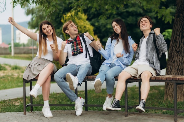 Fröhliche multiethnische Freunde, die im Park sitzen und eine Freudengeste zeigen