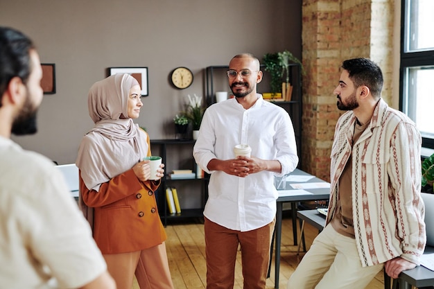 Fröhliche muslimische Kollegen versammelten sich zur Diskussion im Großraumbüro