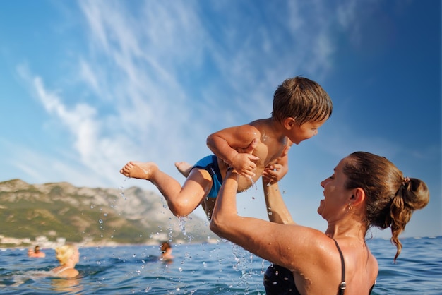 Fröhliche Mutter spielt mit ihrem Sohn im Meer