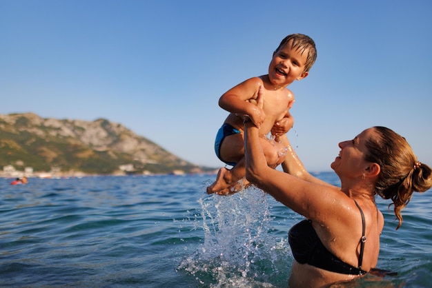 Fröhliche Mutter spielt mit ihrem Sohn im Meer