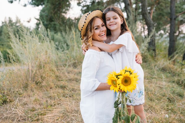 Fröhliche Mutter und ihre kleine Tochter haben gemeinsam Spaß auf der Sommeroberfläche