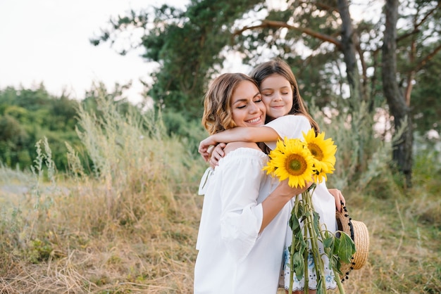 Fröhliche Mutter und ihre kleine Tochter haben gemeinsam Spaß auf der Sommeroberfläche