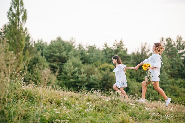 Fröhliche Mutter und ihre kleine Tochter haben gemeinsam Spaß auf der Sommeroberfläche