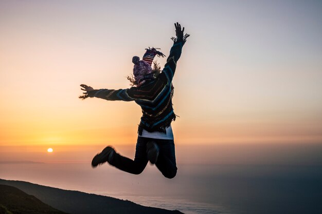 Fröhliche, nicht wiederzuerkennende Menschen, die von hinten betrachtet werden, genießen den alternativen Urlaub und die Freizeitaktivitäten im Freien, die glücklich vor Freude über den fantastischen Sonnenuntergang vor der Tür springen