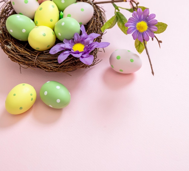 Fröhliche Ostereier in Pastellfarben in einem Nest auf rosa Hintergrund