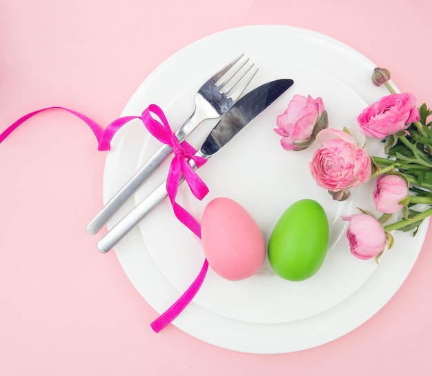 Fröhliche Osterfeier Tisch Ostereier und Blumendekoration auf Platten rosa Hintergrund