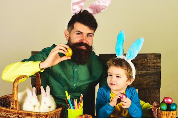 Fröhliche Osterfeier Vater und Sohn mit bemalten bunten Eiern glückliche Familie in Hasenohren