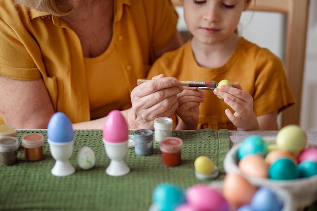 Fröhliche osterhände schließen Großmutter und Mutter mit kleiner Enkelin malen Eier