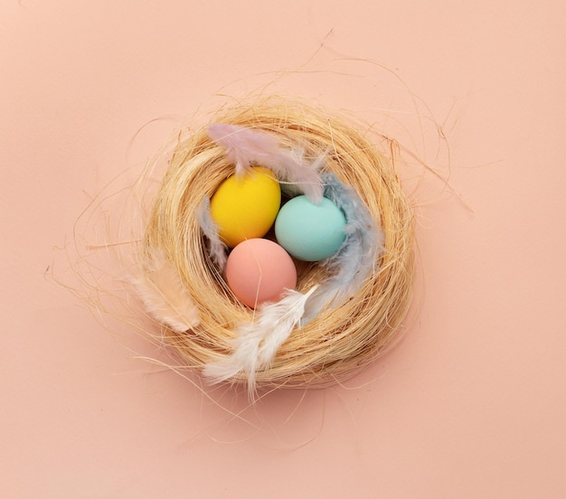 Fröhliche Osterkarte färbte gelbe rosa blaue Ostereier auf einem beigen Nesthintergrund