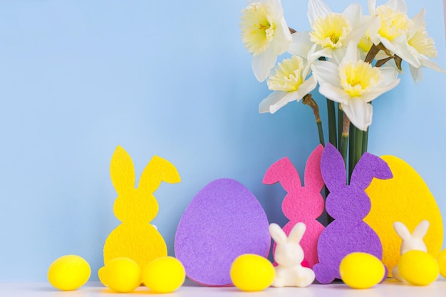 Fröhliche Ostern Bunte Osterhasen Eiern Narzissen auf blauem Hintergrund mit Platz für Text