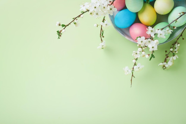 Fröhliche Ostern Gefärbte Ostereier auf rustikalem Tisch mit Kirschblütenbaumzweig auf grünem Hintergrund Osterfeiertagskartenhintergrund mit Kopienraum Ansicht von oben