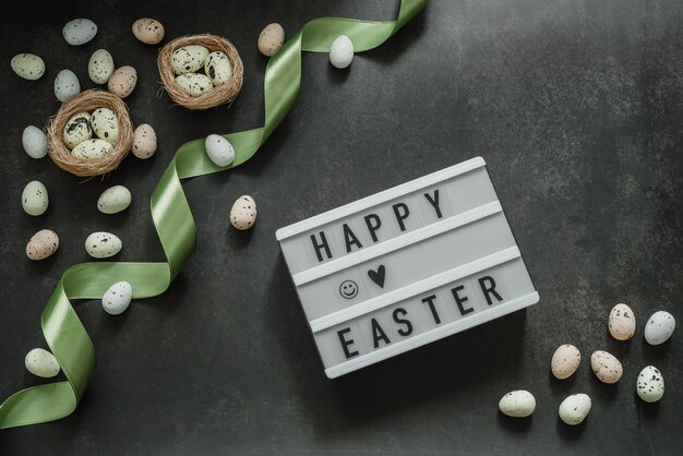 Fröhliche Ostern-Leuchtkasten mit bunten Ostereiern im Vogelnest auf dunklem Hintergrund