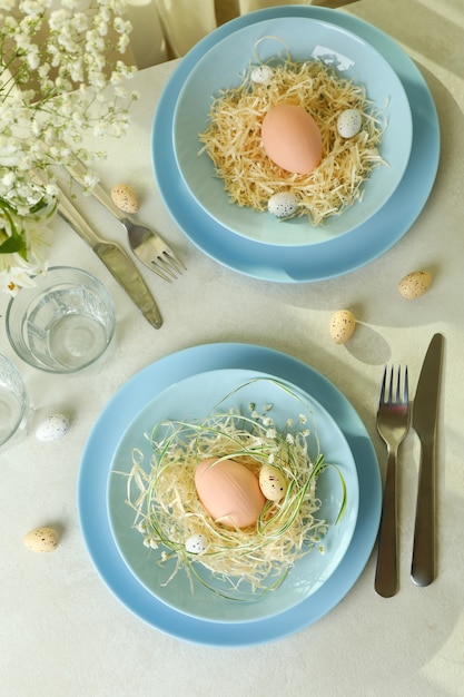 Fröhliche Ostertabelleneinstellung mit Eiern auf weißem strukturiertem Tisch
