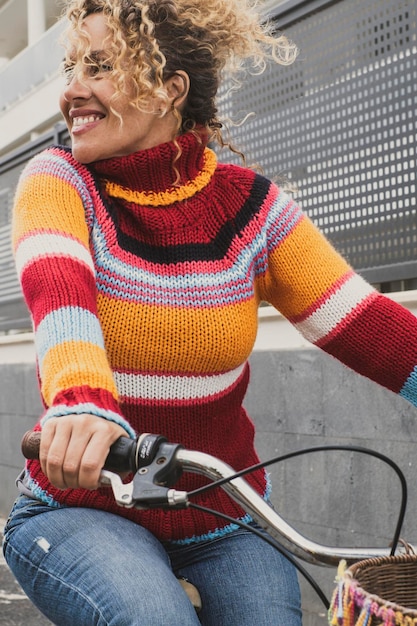 Fröhliche reife junge Frau, die Fahrrad fährt und lächelt und aktive, gesunde Freizeitaktivitäten im Freien genießt. Grüne Atmosphäre und Umwelt, Fortbewegungsmittel mit weiblichen Menschen, die Fahrrad benutzen