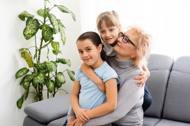 Fröhliche reife Oma mittleren Alters und kleine Vorschulkinder, zwei Enkelinnen, die Spaß beim Spielen zu Hause haben.