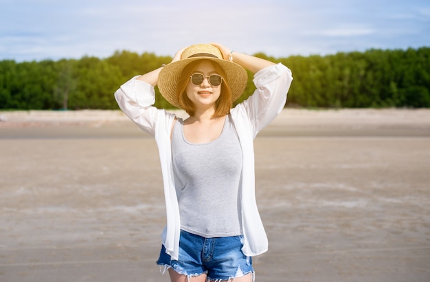 Fröhliche Reisende asiatische Frau mit Hut und Brille am Strand, genießen und entspannende Zeit