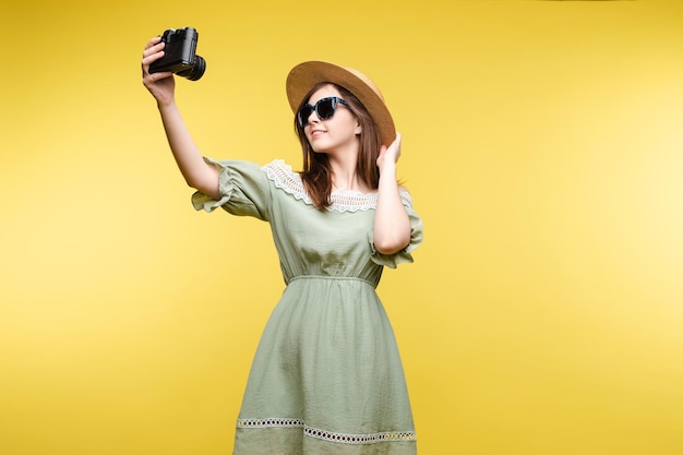 Fröhliche Reisende, die posiert und Selfie mit der Kamera macht, die auf gelbem Studiohintergrund isoliert ist