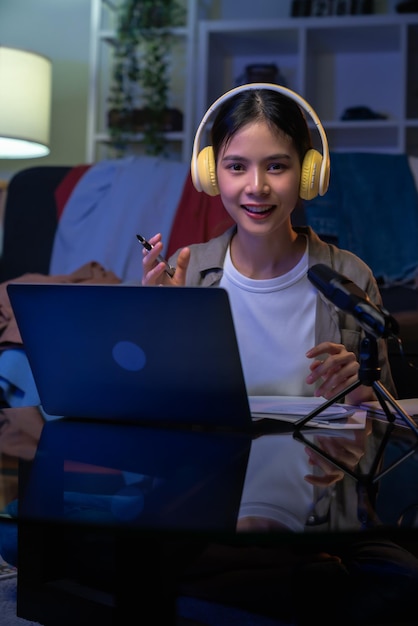 Foto fröhliche schöne asiatische frau in einem weißen t-shirt mit kopfhörern und laptop bei videoanrufen und online-studium im internet.