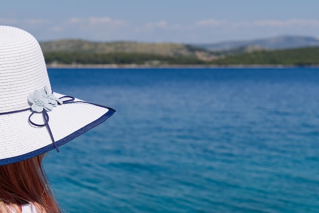 Fröhliche, schöne junge Frau, die die Freiheit und die Sommerferien mit Meerblick genießt