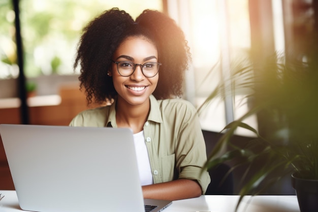Fröhliche schwarze Frau arbeitet an einem Laptop in einem hellen Büro