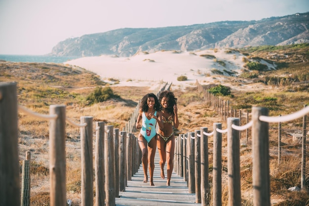 Fröhliche schwarze Frauen, die auf dem Pier laufen