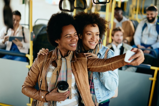 Foto fröhliche schwarze frauen, die sich beim selfie in einem bus amüsieren